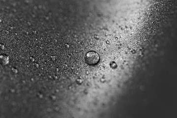Grainy gray background with water drops. Metallic titanium texture of the pan.