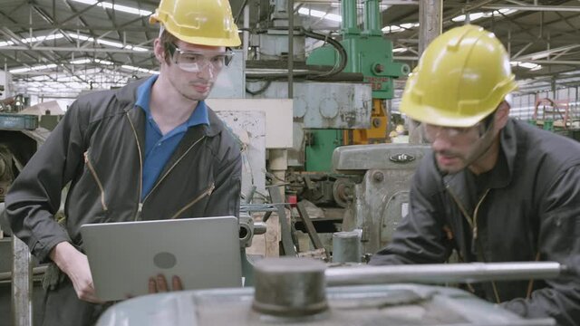 Team engineer working looking laptop computer, two man planning project, technician inspect and fix machine, entrepreneur management and control in factory, industrial and construction concept.