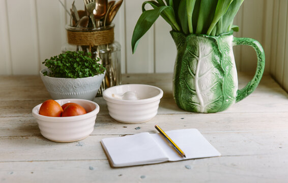Kitchen counter, with black shopping list, spring flowers and kitchen essentials.