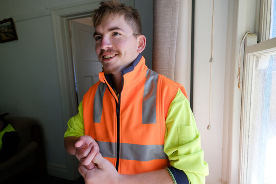 Man with High-Visibility Tops Standing at Window
