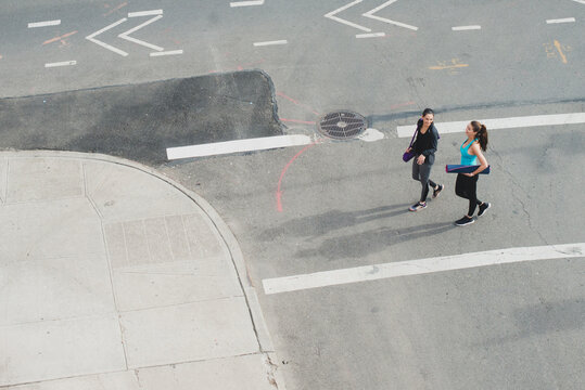 Athletic women walking in city with yoga mats