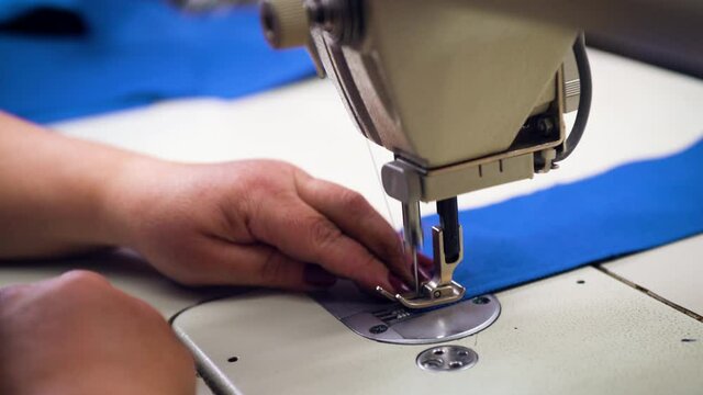 Closeup of female hands working on a sewing machine.