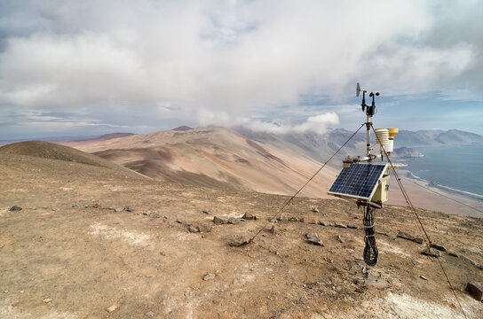 Solar panel at the cliff in desert, ocean below and cloud above