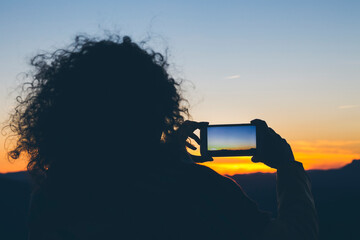 Woman taking a photo at sunset