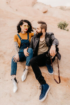 Tattooed couple sitting in love in the desert