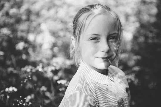 Black and white image of a smiling child in a woodland setting.