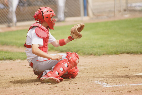 A catcher in a low stance behind the home plate