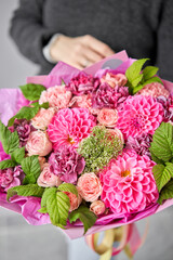 Red tones Beautiful bouquet of mixed flowers in womans hands. the work of the florist at a flower shop. Handsome fresh bouquet. Flowers delivery