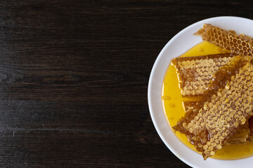 Honeycombs in white plate on the wooden table. Natural organic bee product. Healthy lifestyle. Copy space for your text. Close-up photo.