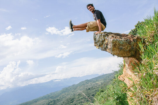Man having fun on a rock elevating his feet on natural landscape. Adventure travel