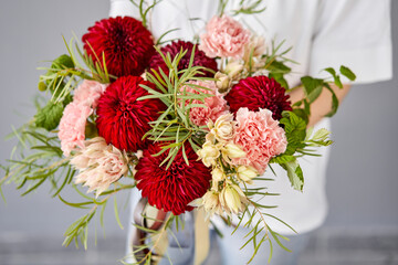 Red tones Beautiful bouquet of mixed flowers in womans hands. the work of the florist at a flower shop. Handsome fresh bouquet. Flowers delivery