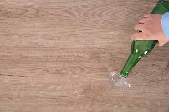 Hand holding wine bottle and wine glass on the table