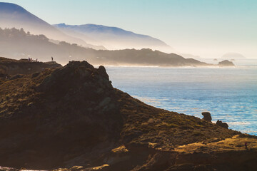 Fototapeta na wymiar Hikers on Sea Lion Point With Big Sur Coastline in the Distance, Point Lobos, SNR, Big Sur, California, USA