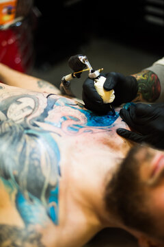Making Tattoo: a man continue his work in progress tattoo on his chest