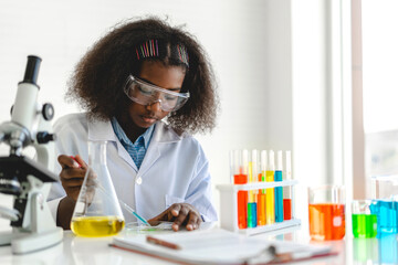 African american cute little girl student child learning research and doing a chemical experiment while making analyzing and mixing liquid in glass at science class on the table.Education 