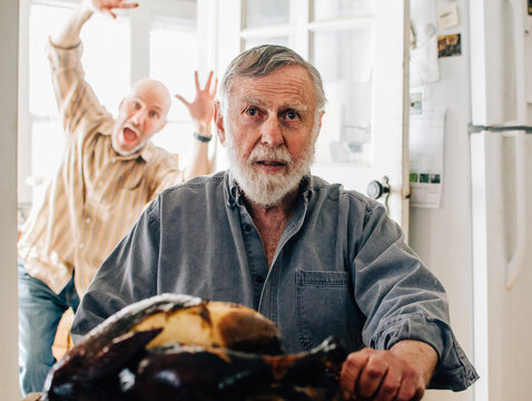 man photobombs another man who is carving a turkey