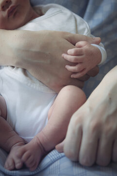 Hands of a mother holding her one-day-old baby boy