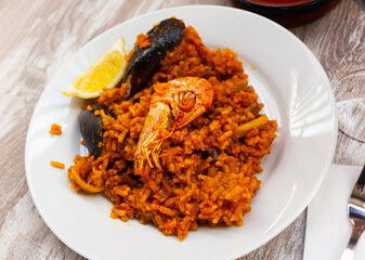 Appetizing racy seafood paella with mussels, prawns and slice of fresh lemon.Traditional Valencian cuisine