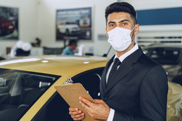 Man car dealer wearing protective medical mask on his working place