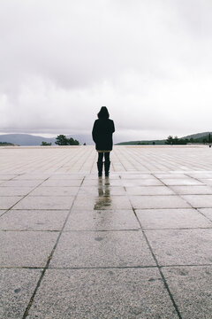 Fashion portrait of woman facing back with parka coat on a rainy day