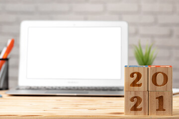 Wooden cubes 2021 Year on working table with open laptop