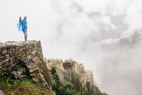 Young happy man on ancient ruins over clouds - Machu Picchu, Peru