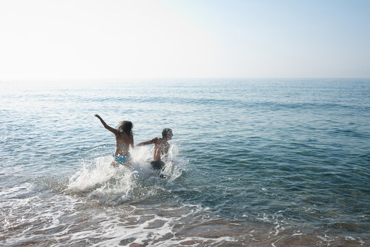 Young couple splashing at the ocean
