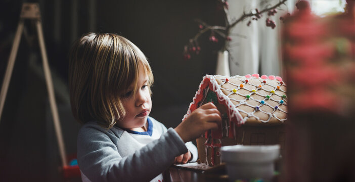 Cute preschool age girl building gingerbread house at Christmas time