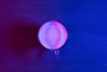 Instant coffee cup on the table in the neon lights background.