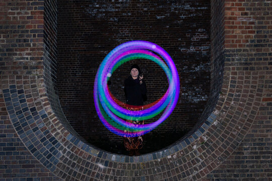Glowing trails of light made by a Poi dancer using led glow poi's within the arches of a viaduct