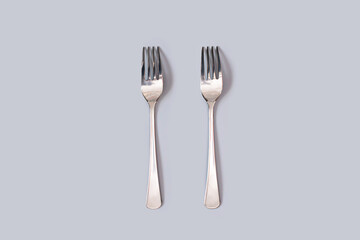 two forks in the center of the frame on a gray background