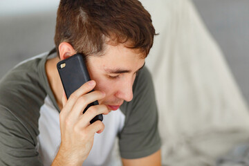 brunette man in light t-shirt talking on the phone, natural light, daytime