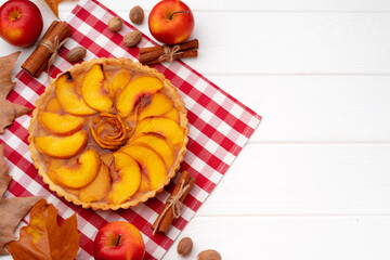 Autumn thankgiving pie on white wooden board decorated with dry leaves and cinnamon sticks
