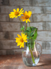 Bouquet of yellow rudebekia in a glass jug on a wooden table rutik kitchen