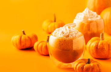 Total orange pumpkin spiced latte or coffee in double glass cup. Autumn or winter hot drink in festive table setting