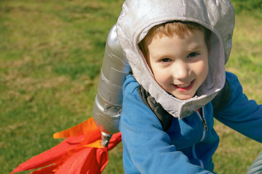 Boy smiles at camera wearing homemade rocket pack and helmet