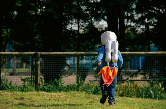 Child runs in park wearing homemade rocket pack
