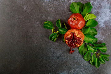 Pomegranate with seeds and leaves on dark background.