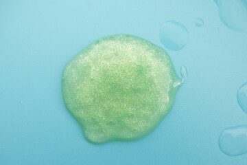 Green cosmetic cream lotion moisturizer strokes on pastel blue. Hygiene, skincare product creamy texture. Beauty face creme smear smudge swatch on color background