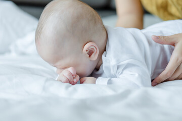 Happy mom and baby playing together on the bed at home . family love concept.