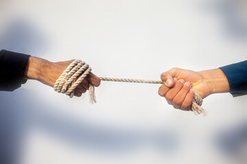 Close up shot of two male hand playing tug of war over blurred background.