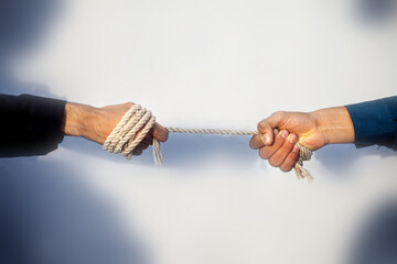 Close up shot of two male hand playing tug of war over blurred background.