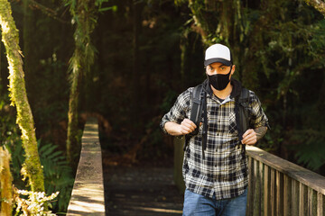 Man wearing face mask on a wooden bridge on the forest. New tourism during Covid-19 pandemic disease