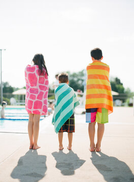 kids standing at pool with colorful towels