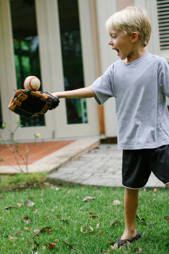 young boy playing catch in the backyard