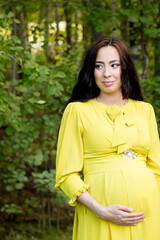 Pregnant woman in yellow dress in nature