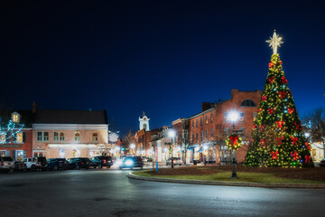 Decorated Christmas tree lit up at night with a star in the quaint village town square of historic...