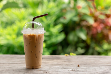 Iced coffee on wooden table and blurred green nature background