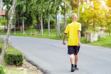 Back view portrait of a Asian elderly man in fitness wear walking and jogging for good health in...