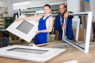 Happy brigade of two people working at workshop for production of plastic windows